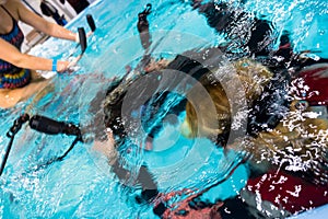 Underwater photography. The girl takes off the aqua trainer for classes in the pool