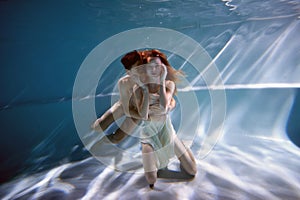 Underwater in the pool with the purest water. Loving couple hugging. The feeling of love and closeness. Soft focus