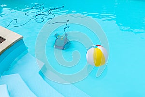 Underwater Robot cleaning a swimming pool and a inflatable ball floating