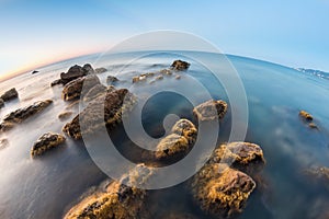 Underwater rocks at sunrise on beach