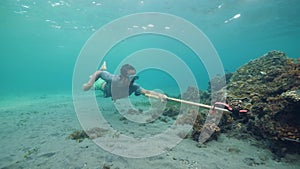 Underwater scene, a fish hunter try to catch a fish using wooden speargun.