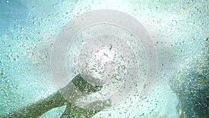 An underwater shot of a jumping man against bright sunshine.Slow motion video.