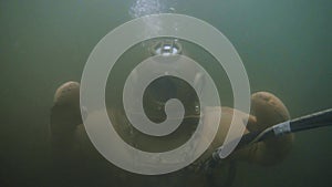 Underwater slowmotion view of a diver wearing a large round helmet