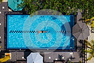 Underwater swimmer man diving in the luxury villa swimming pool. Aerial top shot. Careless summer vacation concept image