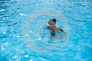 Underwater teen boy in the swimming pool with goggles in sunny day. Children Summer Fun. Kids water sport activity on