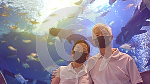 Underwater tunnel aquarium with Asian senior elder couple wear mask dating have fun happy