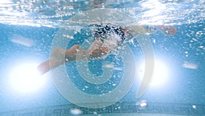 Underwater view on cute little boy in infltable ring swimming in pool. Concept of children healthcare and sports.