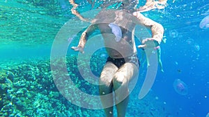 Underwater view of an elderly man swiming in the clear water of the Red Sea. Egypt