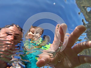 Underwater view of a father and her daughter with distorted face