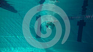 Underwater view of girl jumping in the pool, slow motion. Underwater view. Night shot.