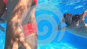 Underwater view of having fun children jumping and diving into swimming pool