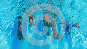 Underwater view of people legs dangling in clear pool water
