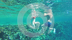 Underwater view of people swimming in the Red Sea near a coral reef and exotic fish. Egypt