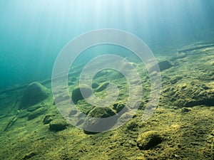 Underwater view of sloping lake bottom with sunrays