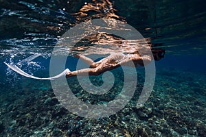 Underwater view of woman swimming near corals in transparent ocean