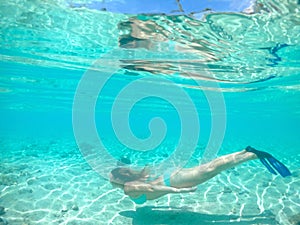 UNDERWATER: Young woman on vacation snorkeling in the perfect tropical water.