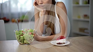 Underweight girl choosing between cake and salad, healthy vs high-calorie food