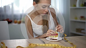 Underweight girl measuring piece of cake with tape, fear of gaining weight