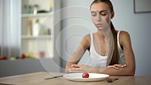 Underweight woman looking at small portion of meal, exhausted body, severe diets