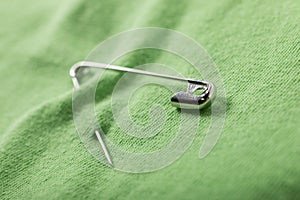 Undo safety pin halfway fastened on a green cloth