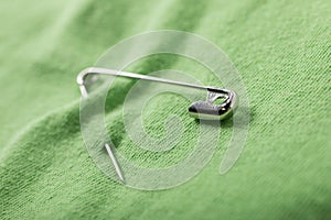 Undo safety pin halfway fastened on a green cloth photo