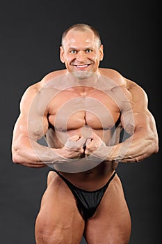 Undressed bodybuilder demonstrates arm muscles