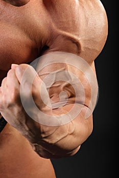 Undressed bodybuilder demonstrates biceps