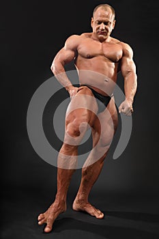Undressed bodybuilder touches floor by toe