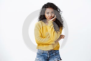 Uneasy and sad cute african american curly-haired girl in yellow sweater feeling lonely and bored, lean head on palm photo