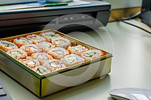 uneaten sushi rolls in a bento box left on an office desk