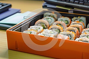 uneaten sushi rolls in a bento box left on an office desk
