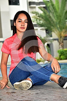 Unemotional Filipina Teenager Girl Sitting By Pool