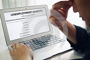 Unemployed depressed person filling out an online unemployment benefits application form using laptop computer