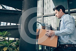 Unemployed hold cardboard box and laptop bag, dossier and drawing tube in box. Quiting a job, businessman fired or leave a job