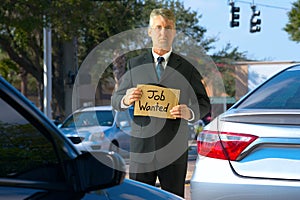 Unemployed panhandler man at traffic intersection with Job Wanted sign