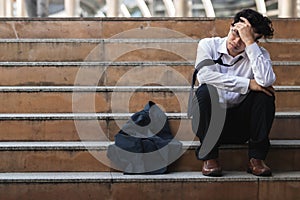 Unemployed stressed young Asian business man in suit covering face with hands. Failure and layoff concept