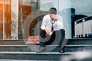 Unemployed tired or stressed businessman sitting on the walkway photo