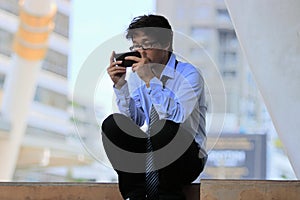 Unemployed young Asian businessman using mobile smart phone find a job. Depressed unemployment business concept.