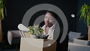 Unemployment Concept. Upset Fired Black Female Employee Holding Box Of Personal Stuff