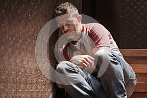 Unemployment and divorce - dramatic lifestyle portrait of sad and depressed man on his 40s sitting indoors on staircase thoughtful