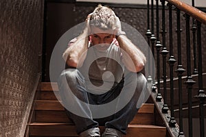 Unemployment and divorce - dramatic lifestyle portrait of sad and depressed man on his 40s sitting indoors on staircase thoughtful