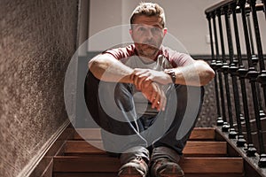 Unemployment and divorce - dramatic lifestyle portrait of sad and depressed man on his 40s sitting indoors on staircase thoughtful