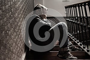 Unemployment and divorce - dramatic lifestyle portrait of sad and depressed man on his 40s sitting indoors on staircase thoughtful