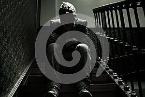 Unemployment and divorce - dramatic lifestyle portrait of sad and depressed man on his 40s sitting indoors on staircase thoughtful