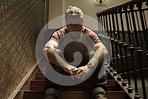 Unemployment and divorce - dramatic lifestyle portrait of sad and depressed man on his 40s sitting indoors on staircase thoughtful