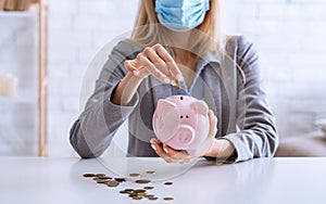 Unemployment during epidemic. Woman puts coins into piggy bank photo