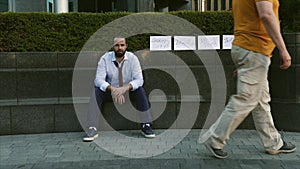 Unemployment, unemployed person, dismissal, downsizing. A man without a job. A young man sits on the street with a sign