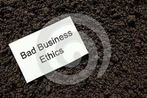 Unethical practices or bad ethics in business concept. Piece of paper with handwritten note on dark soil.