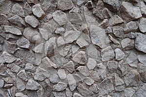 Uneven surface of gray gravel pebble dash on the wall