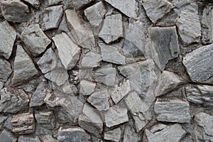 Uneven surface of gray gravel pebble dash on the wall